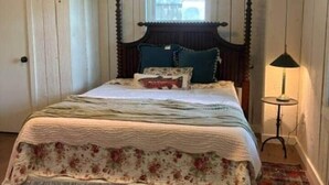A bedroom with a wooden bed, a window, a lamp, and a radiator. - The Bungalow at Bear Creek (Tishomingo County)