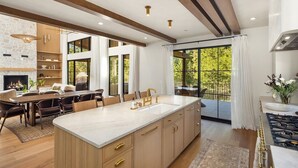 Une cuisine spacieuse dotée d’un grand îlot central, de meubles en bois et d’une cheminée en pierre.