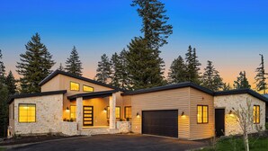 Une maison moderne à deux étages, dotée d’une façade en pierre, d’un garage et d’une allée.
