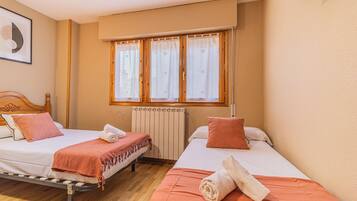 Habitación de hotel con dos camas, un radiador y una ventana con cortinas.