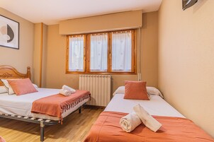 Habitación de hotel con dos camas, un radiador y una ventana con cortinas.