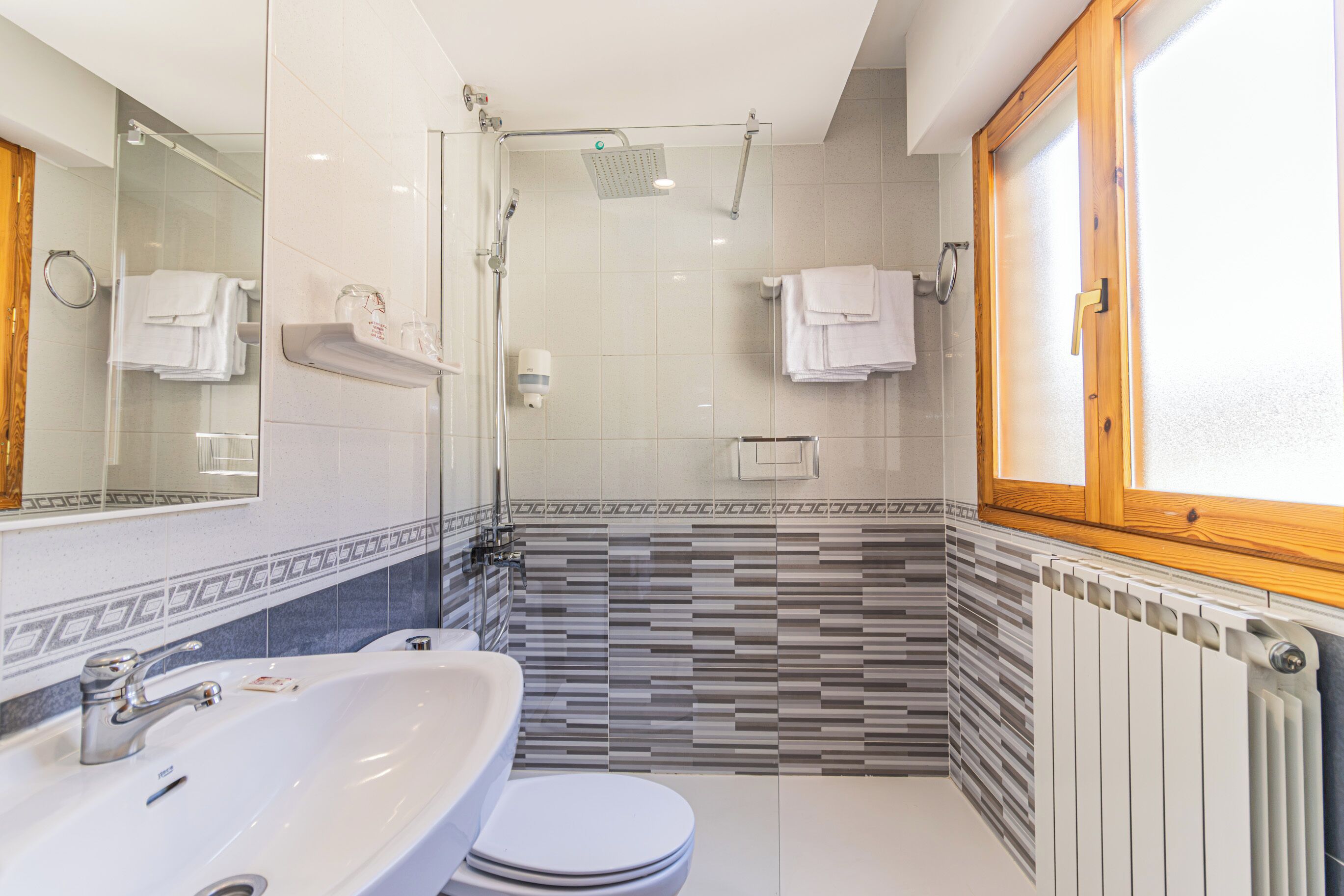 Un baño moderno con cabina de ducha de vidrio, un lavabo blanco y un inodoro.
