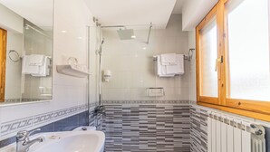 Um banheiro moderno com box de vidro, pia branca e vaso sanitário.