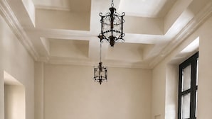 A bedroom with a bed, a nightstand, a dresser, a chandelier, and a window.