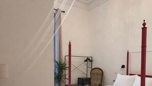 A bedroom with a four-poster bed, a desk, and a chair.