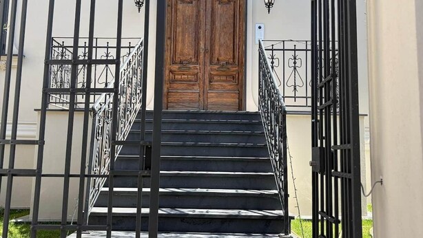 A set of black metal stairs leading to a wooden double door with a decorative arch above it.