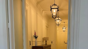 A hallway with a checkered floor, a wooden dresser, and a vase with flowers.