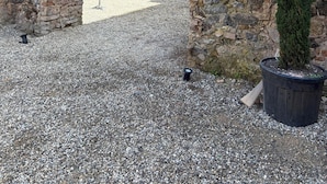 An ancient stone archway, a potted evergreen tree, and a gravel courtyard.