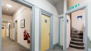 Hotellin käytävä, jossa on palohälytysopasteita, palosammutin ja portaikko.