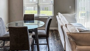 Un espace repas avec une table en verre, des chaises et un luminaire suspendu moderne.