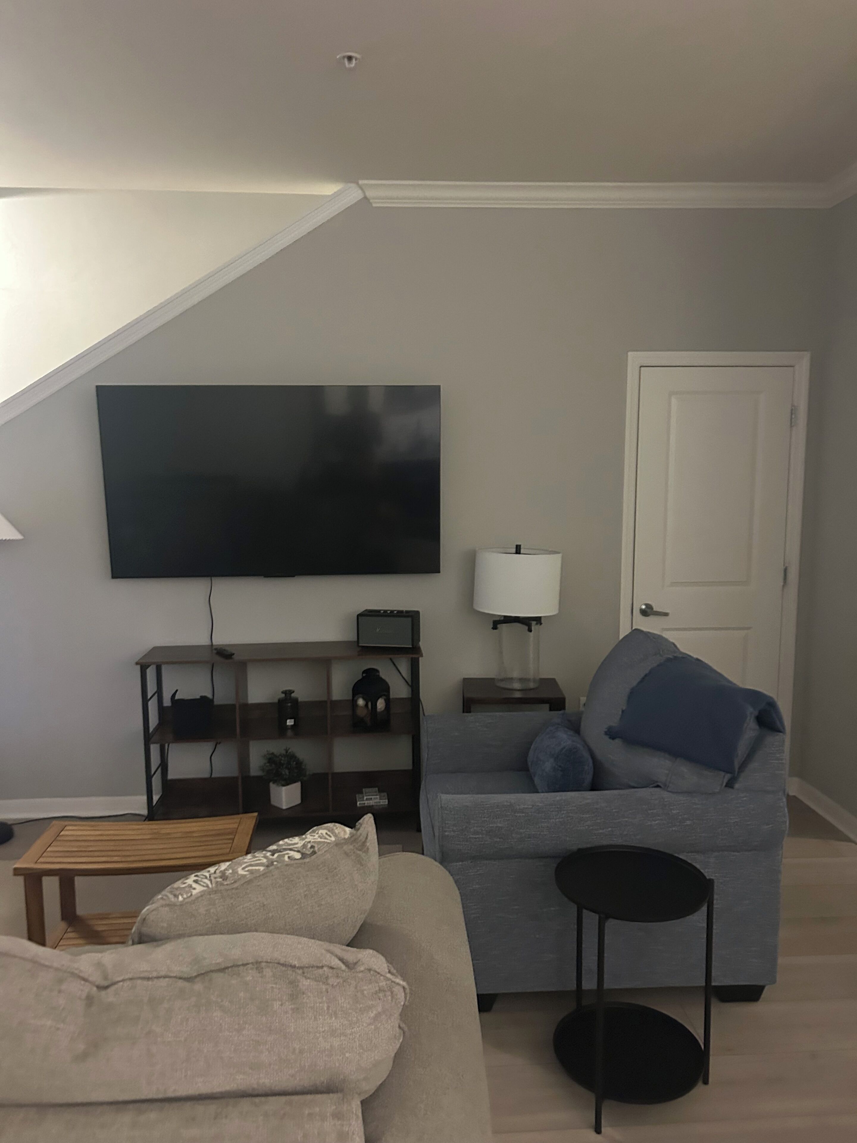 Un salon avec un canapé, une table basse, un téléviseur, une lampe et une porte.