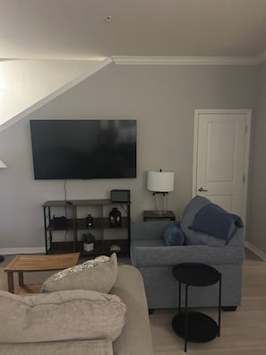A living room with a sofa, a coffee table, a TV, a lamp, and a door.