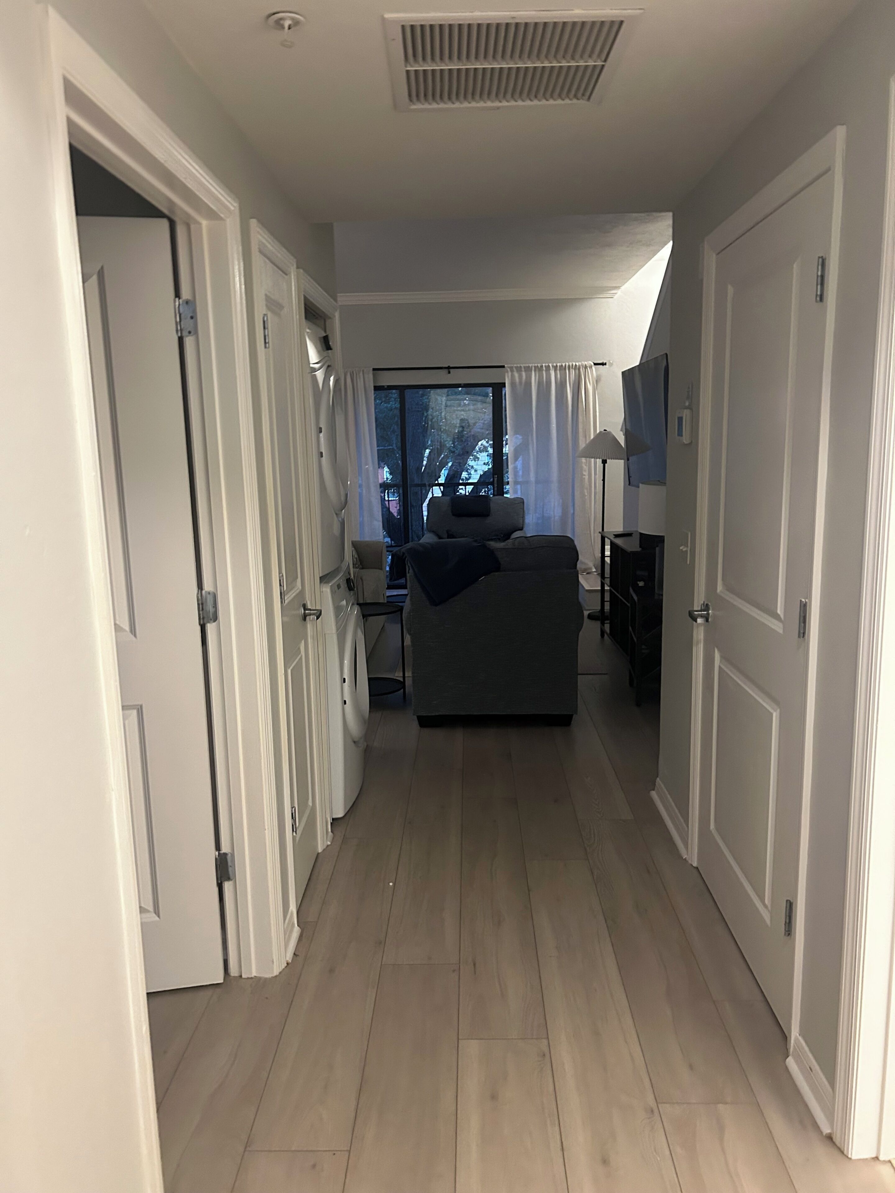 A hallway leading to a bedroom with a window, a sofa, and a desk.