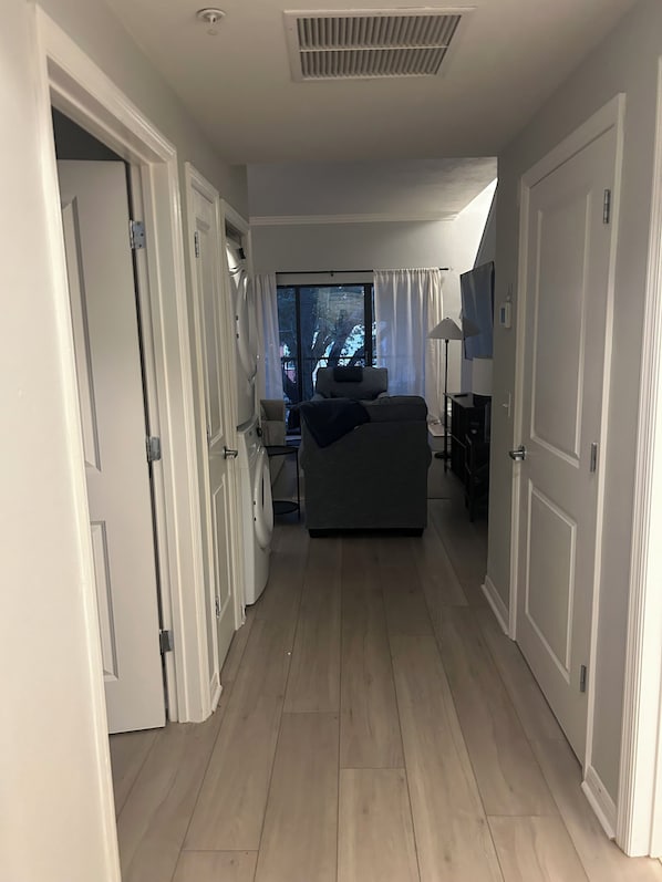 A hallway leading to a bedroom with a window, a sofa, and a desk.