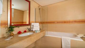 Un baño con bañera, dos lavamanos, cabina de ducha de vidrio y un espejo grande.