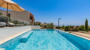 A rooftop swimming pool with clear blue water, a beige umbrella, and a view of the cityscape. - Infinity Blue Green Coast (Himarë)
