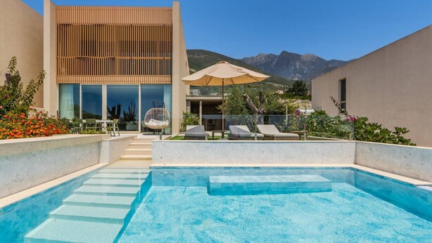 A modern pool area with lounge chairs, a wooden pergola, and a mountain view. - Infinity Blue Green Coast (Himarë)