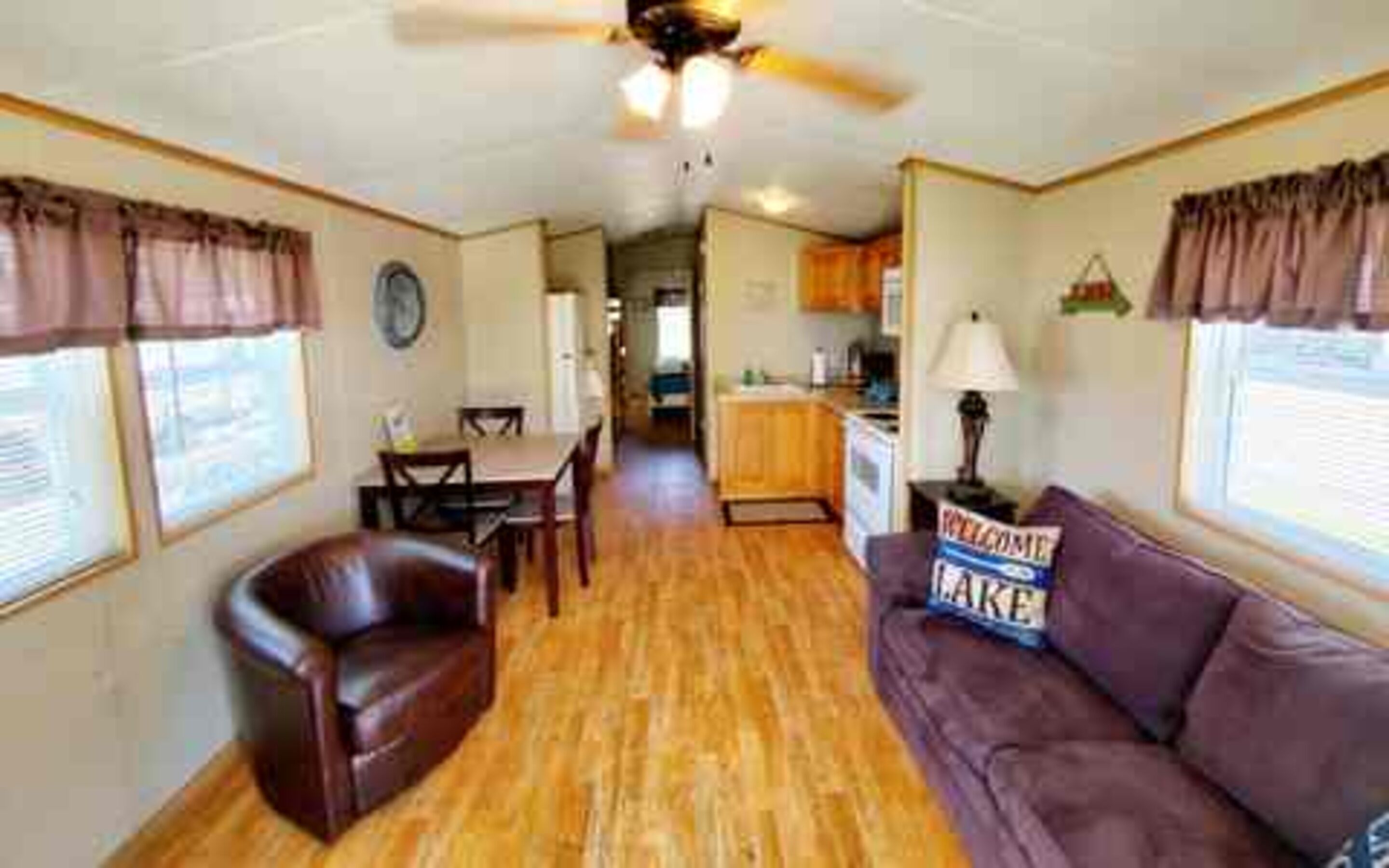 A compact RV interior with a dining area, kitchenette, and a couch.