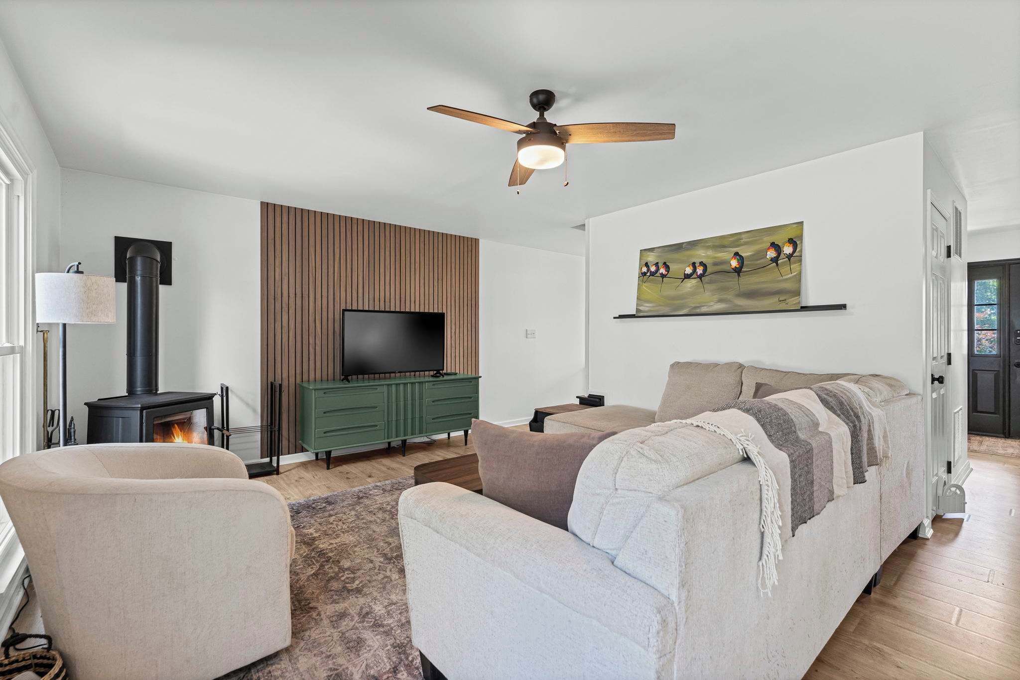 A living room with a sofa, a television, a fireplace, and a ceiling fan.