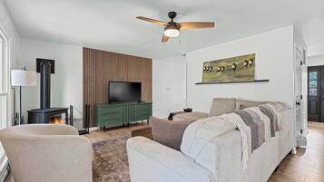 A living room with a sofa, a television, a fireplace, and a ceiling fan.
