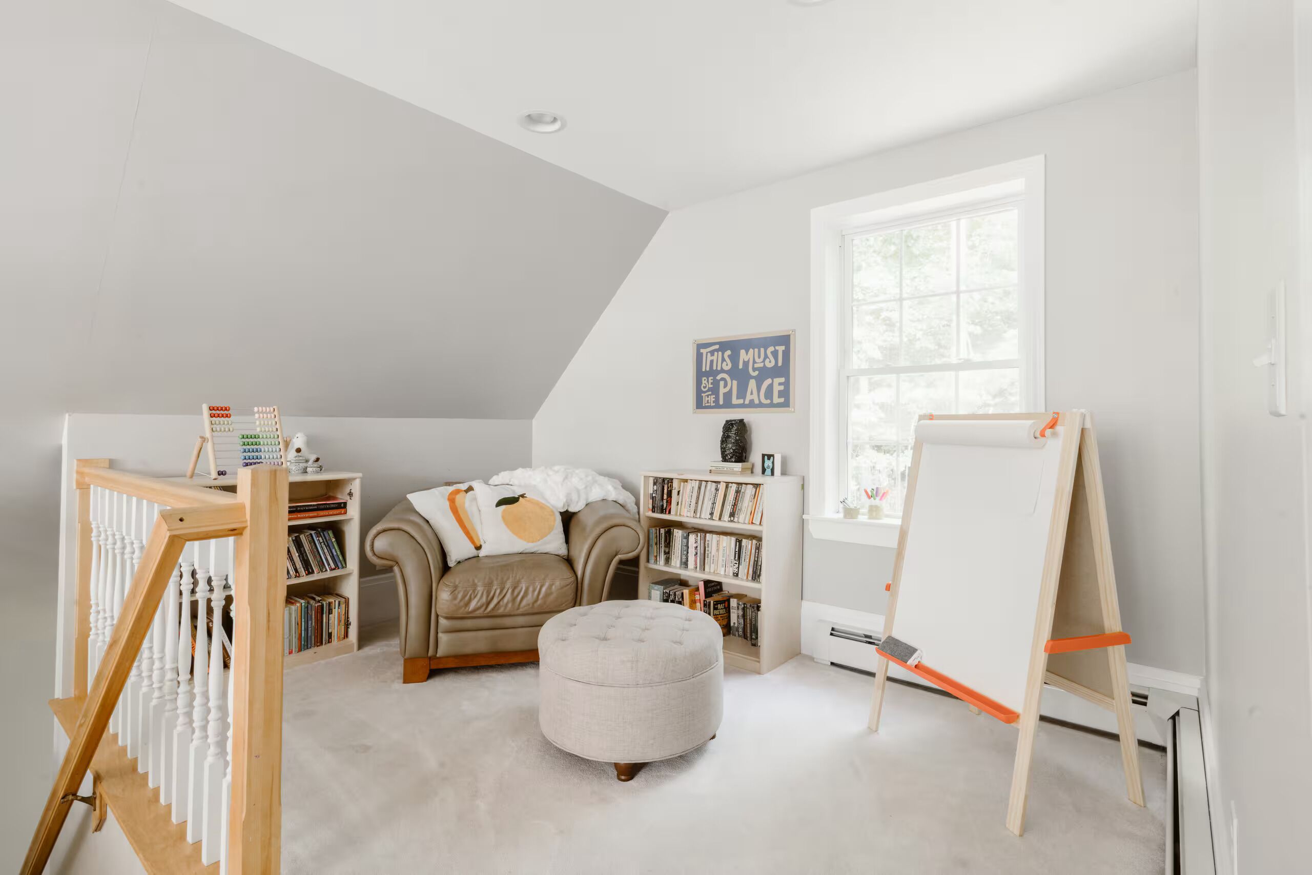 Een kamer met een hoogslaper, een klein voetenbankje, een whiteboard en een boekenkast.