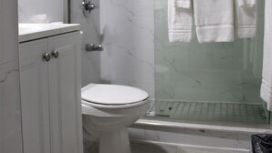 Une salle de bain moderne avec une douche à parois de verre, des toilettes et un meuble-lavabo avec des placards.