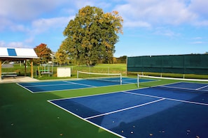 A tennis court with a net, a pavilion, and a large tree. - Thousand Islands Country Club (Wellesley Island)