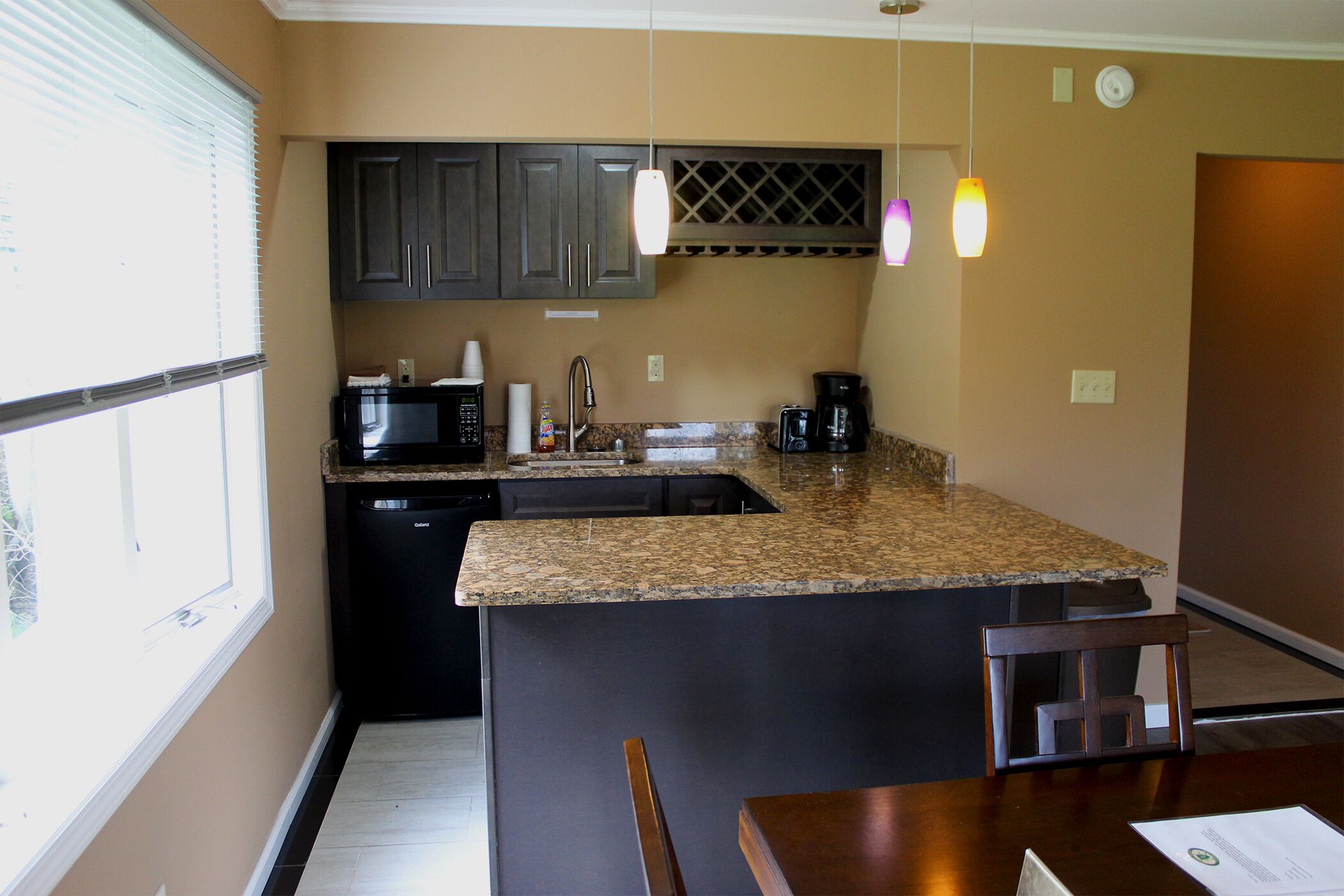 A compact kitchen with a microwave, coffee maker, and sink.