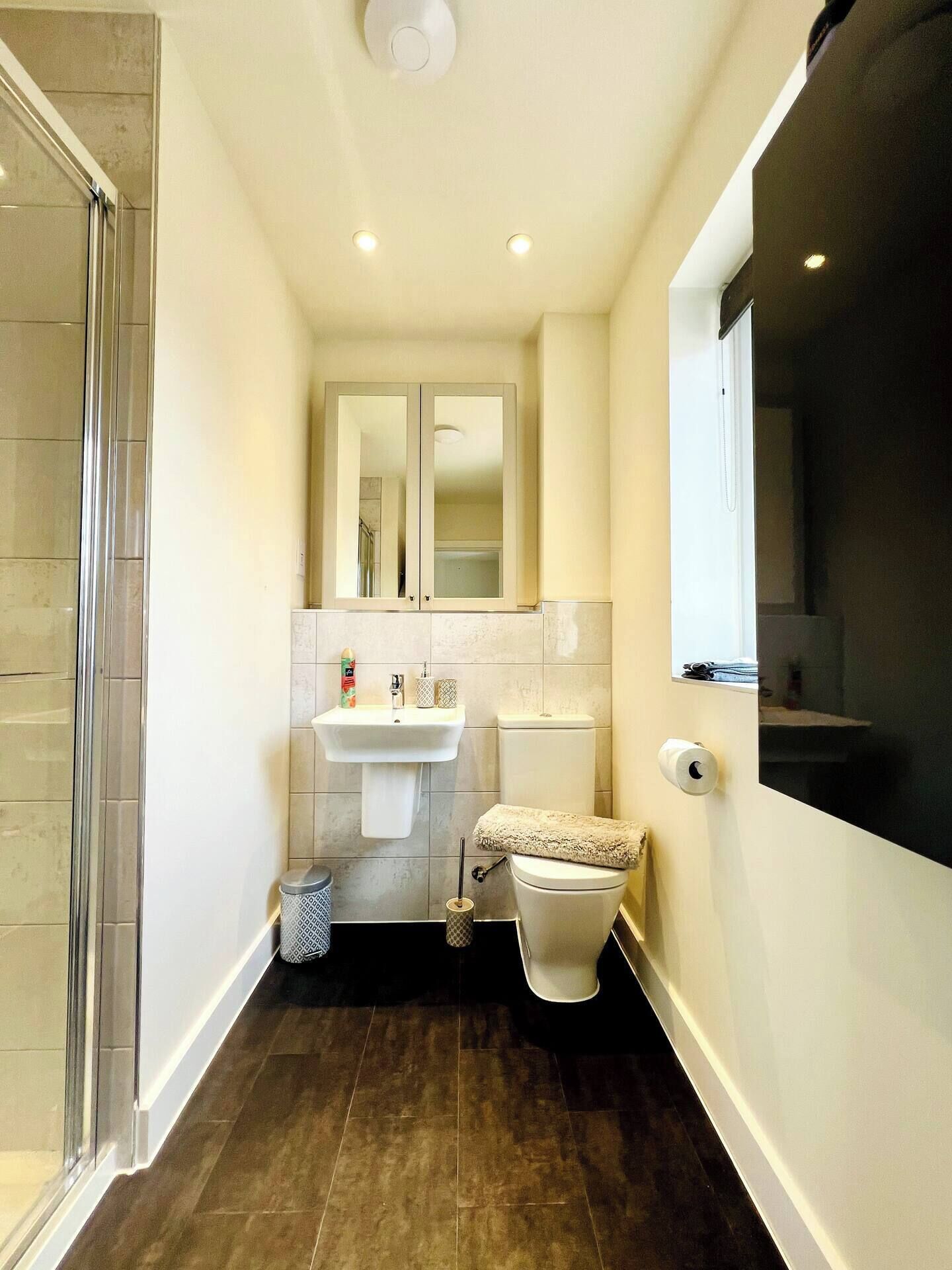 Un baño con ducha, inodoro, lavamanos y espejo.