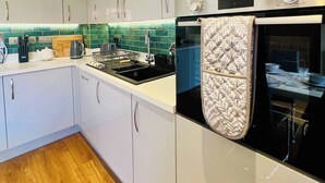Een moderne keuken met witte kasten, een roestvrijstalen oven, en een handdoek met een patroon hangend aan de ovendeur.