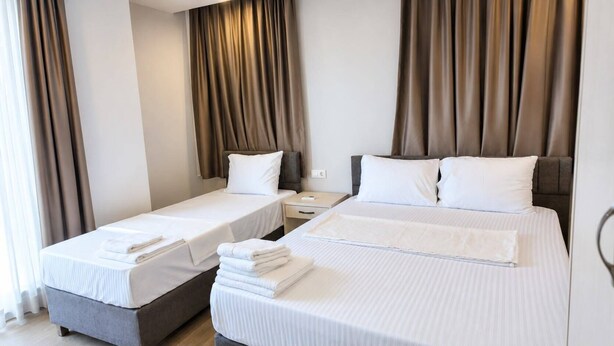 A hotel room with two beds, a nightstand, and a wardrobe.