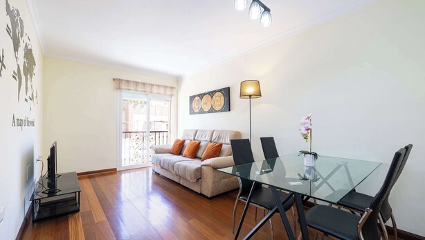 Una sala de estar con una mesa de comedor de vidrio, un sofá y un mueble para televisión.