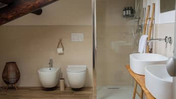 A modern bathroom with a shower, two toilets, a bidet, and a wooden vanity with two sinks.
