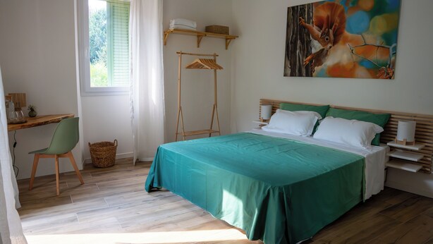 A bedroom with a bed, a desk, a chair, a hanging clothes rack, and a painting on the wall. - Barzy Urban Country House (Como)