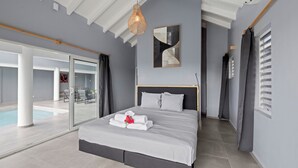 Une chambre d’hôtel moderne avec un grand lit, une vue sur la piscine et un ventilateur de plafond.