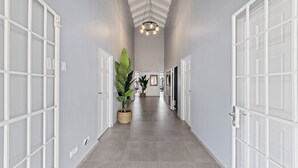 Un couloir avec des portes blanches, un luminaire au plafond et des plantes en pot.