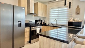 A modern kitchen with a stainless steel refrigerator, a stove, and a microwave. - 3BR Punta Cana Villa Near Beach & Mall| Yellowkey (punta cana)