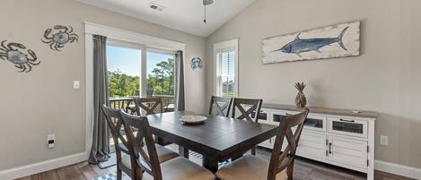 A dining area with a table, chairs, a ceiling fan, and a kitchen area with cabinets.