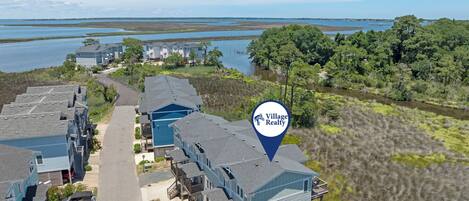 A residential area with multiple two-story buildings, a swimming pool, and a view of a body of water.