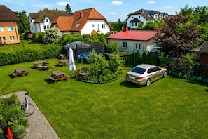 A residential area with houses, a car, and a garden with picnic tables and a swing set.