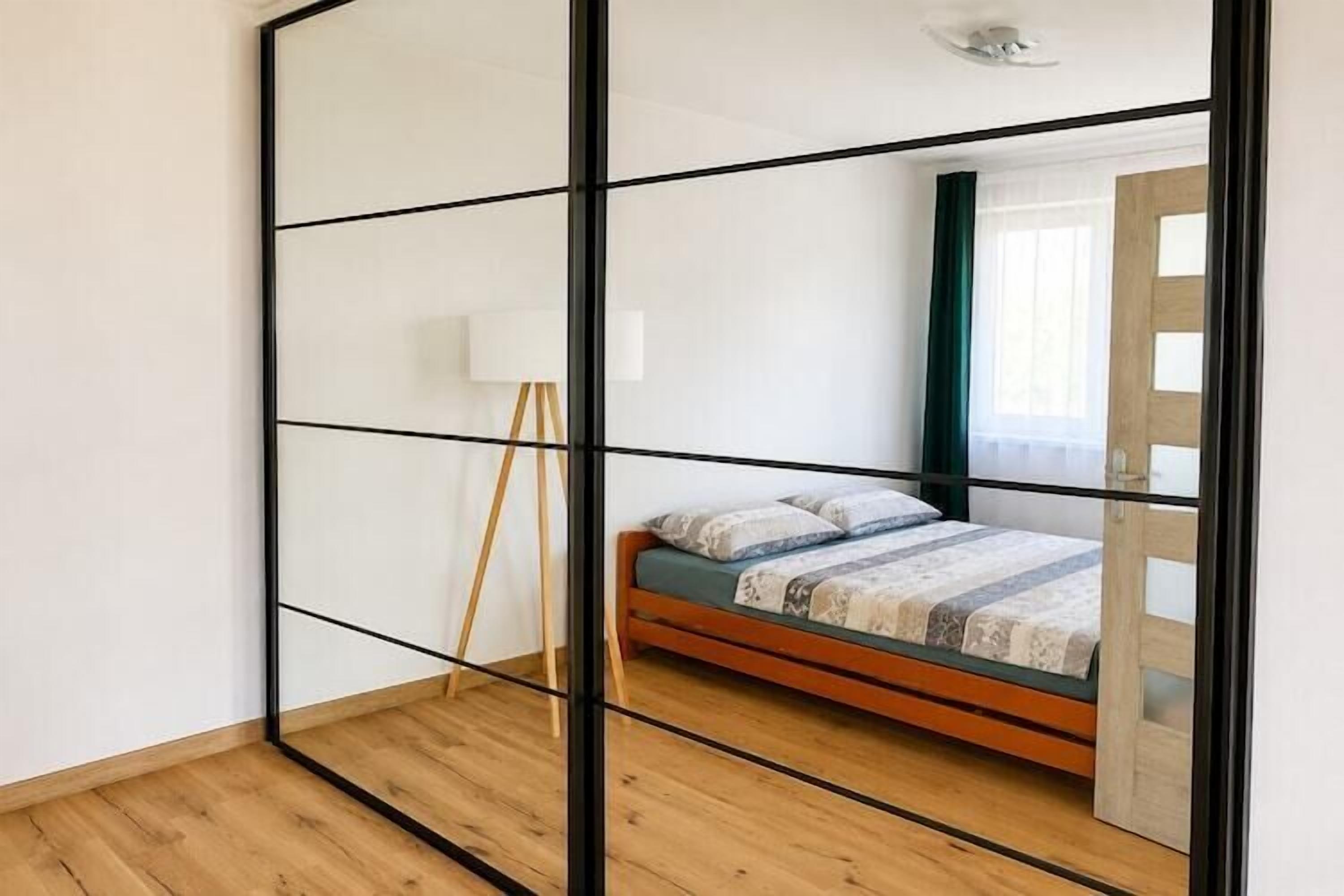 Une pièce avec un lit, une lampe sur pied et une porte coulissante.