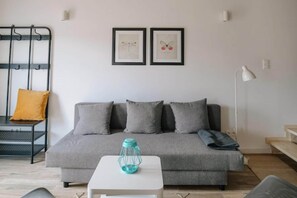 Una sala moderna con un sofá gris, una mesita blanca y un farol azul.