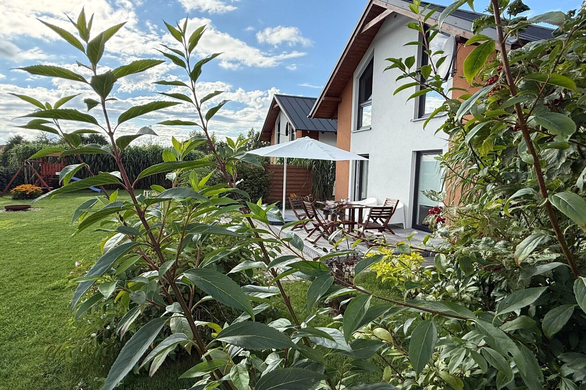 Une maison moderne dotée d’un patio, de mobilier d’extérieur et d’un jardin.