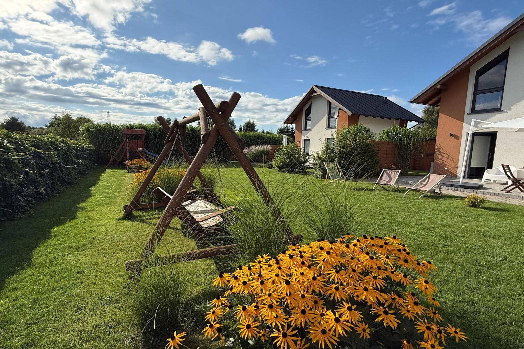 Un jardin résidentiel avec une balançoire, une pelouse et une maison au design moderne.