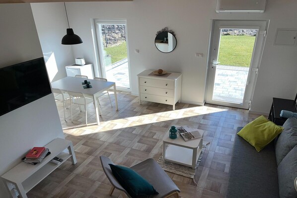 A modern living space with a dining area, a sofa, a coffee table, and a TV.