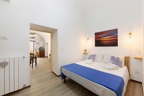 Une chambre à coucher avec un lit, un tableau et une vue sur la cuisine.