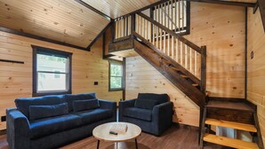 A wooden interior with a staircase, two sofas, a coffee table, and a window. - Route 66 Retreat (Somerset)