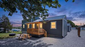 A small, single-story building with a wooden deck and a gravel driveway. - Route 66 Retreat (Somerset)