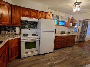 Una cocina con gabinetes de madera, estufa a gas, refrigerador y microondas.