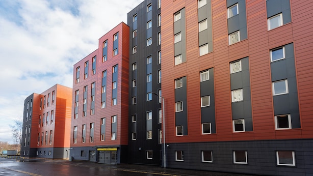 Un edificio de varios pisos con un diseño arquitectónico moderno, que presenta una serie de ventanas rectangulares y un techo plano.